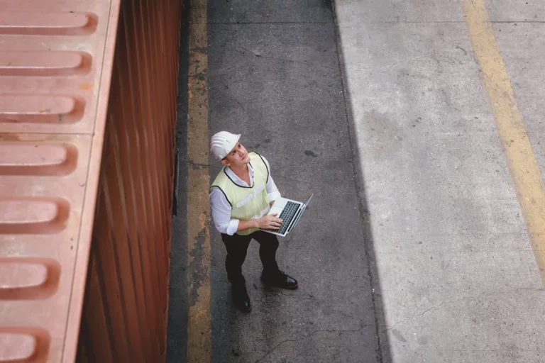 Un ingénieur en transport surveille un entrepôt sur un ordinateur portable à l'aide d'une solution IoT.